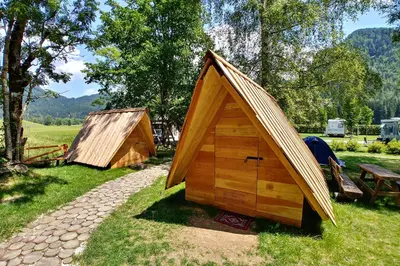 a couple of small wooden shelters in the grass at Camping & Glamping Jezersko ex Cvet Gora in Zgornje Jezersko