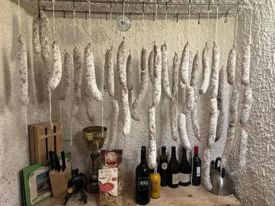 a bunch of meat hanging on a wall with wine bottles at Moulin a Vipava in Renče