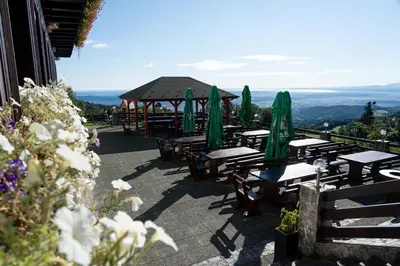 a group of tables and green umbrellas on a patio at Hotel Tisa Pohorje in Pohorje