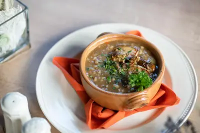 a bowl of soup on a plate on a table at Hotel Tisa Pohorje in Pohorje