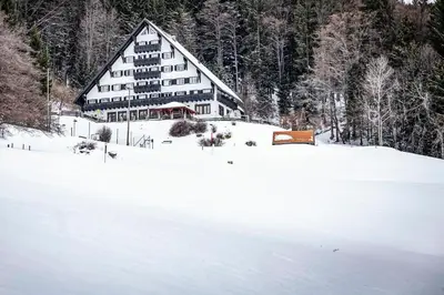 a large building in the snow on a snow covered field at Hotel Tisa Pohorje in Pohorje