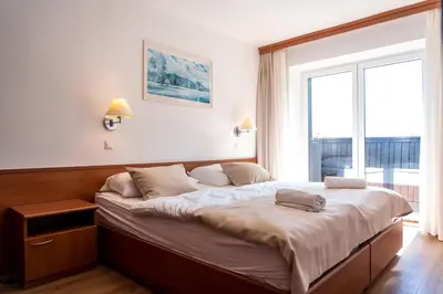 a large bed in a room with a large window at Hotel Tisa Pohorje in Pohorje