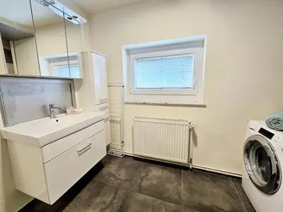a bathroom with a sink and a washing machine at Apartments Rubis in Stožice