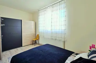 a bedroom with a bed and a chair and a window at Apartments Rubis in Stožice