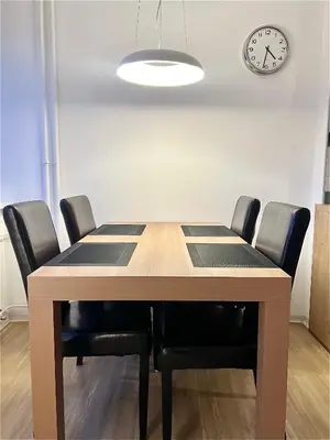 a dining room table with black chairs and a clock at Pero cozy apartment in Ljubljana