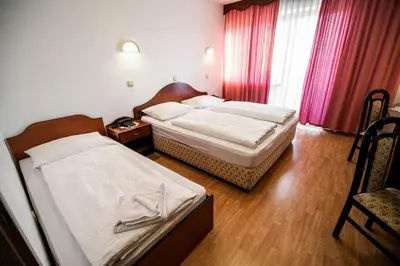 two beds in a hotel room with red curtains at Guesthouse Leski Dvor in Lesce