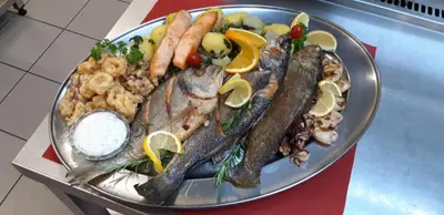a plate of fish and vegetables on a table at Guesthouse Leski Dvor in Lesce