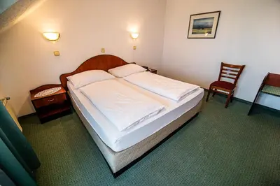 a bedroom with a bed with white sheets and a chair at Guesthouse Leski Dvor in Lesce