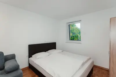 a bedroom with a bed and a chair and a window at Apartmaji Laznik in Ljubno