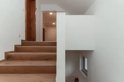 a staircase in a house with white walls and wooden floors at Apartmaji Laznik in Ljubno