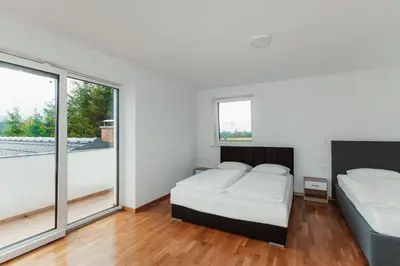 two beds in a bedroom with white walls and windows at Apartmaji Laznik in Ljubno