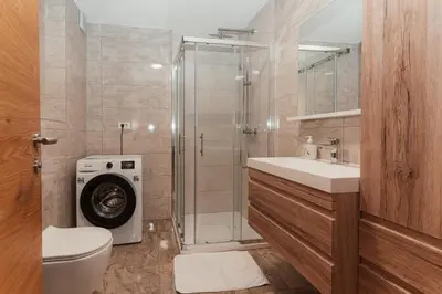 a bathroom with a shower and a washing machine at Apartmaji Laznik in Ljubno