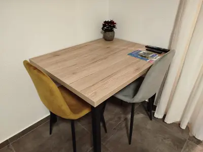 a wooden table with two chairs and a vase of flowers at Apartma Mamut 1850 in Kamnik