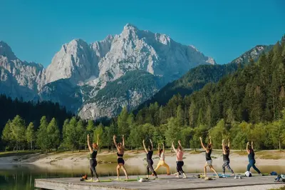 a group of people doing a yoga pose in front of a mountain at Goldhorn Chalet SKI IN&OUT in Kranjska Gora