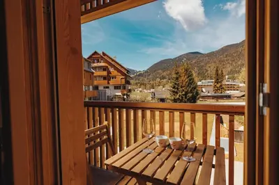 a wooden balcony with a table with wine glasses at Goldhorn Chalet SKI IN&OUT in Kranjska Gora