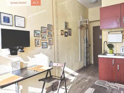 a kitchen with a table and a tv on a wall at Ethno Apartments in Ljubljana