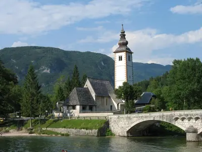 a building with a clock tower next to a bridge at Apartma Jeglic in Bohinj