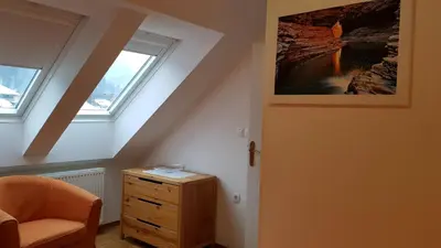 a attic room with a dresser and two windows at Apartma Ravbar in Kranjska Gora