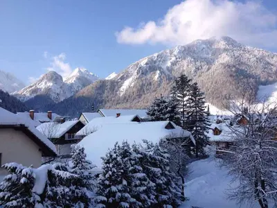 a village covered in snow with mountains in the background at Apartma Ravbar in Kranjska Gora