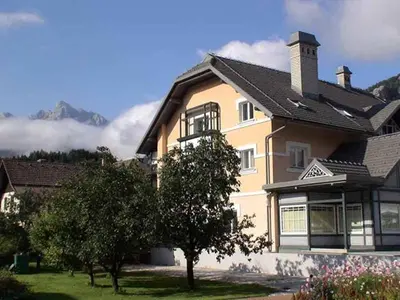 a large house with mountains in the background at Apartma Ravbar in Kranjska Gora