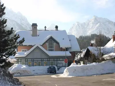 a house covered in snow with a stop sign at Apartma Ravbar in Kranjska Gora