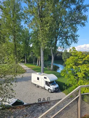 a white truck parked in a parking lot next to a river at L&A Mobile House in Metlika