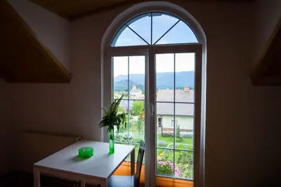 an arched window in a room with a table with a vase at Rooms Ambrožič in Bled