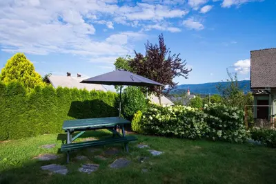 a picnic table with an umbrella in the grass at Rooms Ambrožič in Bled