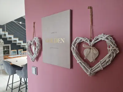 a pink wall with two hearts hanging on it at Hiša Pod Gozdom in Ljubljana
