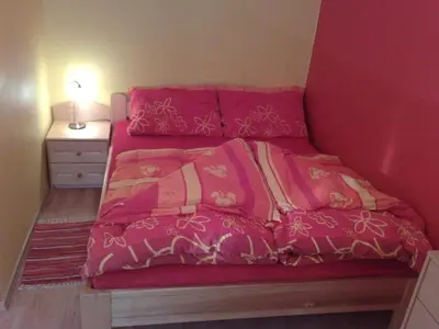 a small bed with pink sheets and a night stand at Apartment Beli Zajec in Mozirje