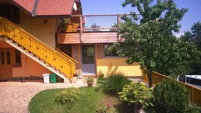 a yellow house with a balcony and a staircase at Apartment Beli Zajec in Mozirje