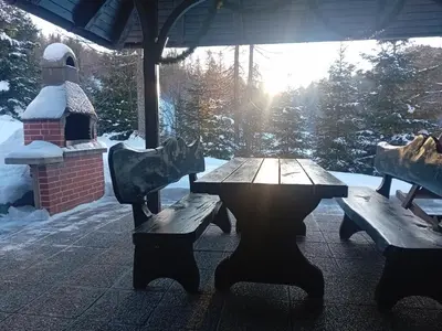 a wooden picnic table and benches in a covered area with snow at Holiday Home Čumar in Cerkno