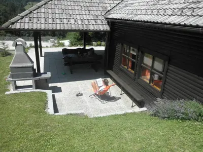 a house with a patio with a bench and a fireplace at Holiday Home Čumar in Cerkno