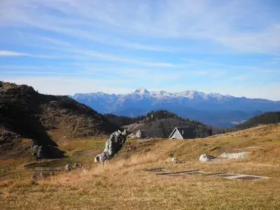a house on a hill with mountains in the background at Holiday Home Čumar in Cerkno
