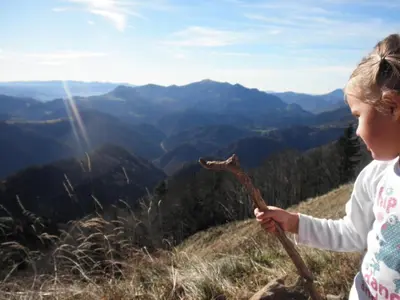 a young girl holding a stick on top of a mountain at Holiday Home Čumar in Cerkno