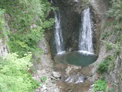 a waterfall on the side of a mountain with a pool of water at Apartments Lovec in Cerkno