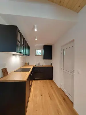 a kitchen with black cabinets and a wooden floor at Cottage at the lake in Preserje