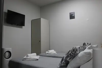 a room with two beds and a tv on the wall at Šeherezada Rooms in Ljubljana