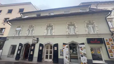 a large white building with a store on a street at Šeherezada Rooms in Ljubljana