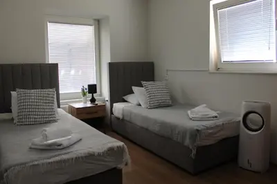 two beds in a room with two windows at Šeherezada Rooms in Ljubljana