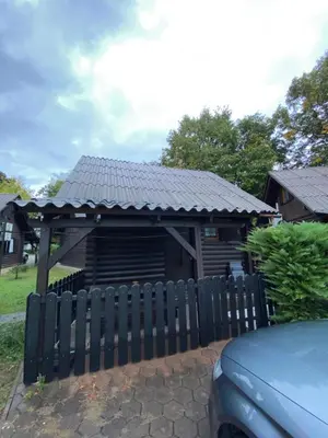 a wooden shed with a black roof behind a fence at Hiška Nisa in Čatež ob Savi