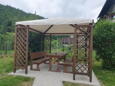 a wooden gazebo with a bench and a table at Fully equipped SIX BEDROOM HOUSE 15 kilometers from LAKE BLED - with a terrace, garden, playground, and parking in Kropa
