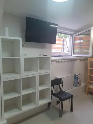 a room with white shelves and a chair and a tv at Fully equipped SIX BEDROOM HOUSE 15 kilometers from LAKE BLED - with a terrace, garden, playground, and parking in Kropa