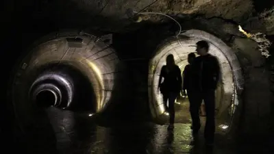two people walking through a dark tunnel at Fully equipped SIX BEDROOM HOUSE 15 kilometers from LAKE BLED - with a terrace, garden, playground, and parking in Kropa