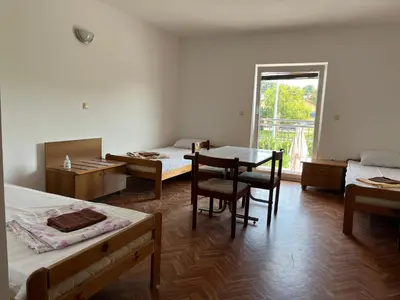 a room with two beds and a table and a window at Prenočišče Buco in Krško