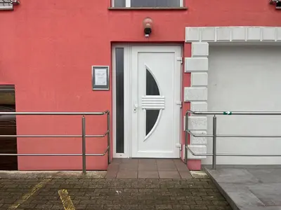 a red building with a white door and a garage at Prenočišče Buco in Krško