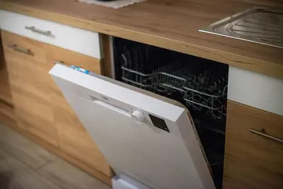 a white dishwasher in a kitchen next to a counter at Apartma Sejalec, Lesce - Bled in Lesce