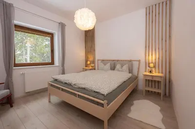 a bedroom with a bed and a window and a chandelier at Apartma Medved - Pokljuka in Zgornje Gorje