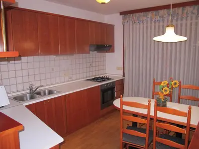 a kitchen with wooden cabinets and a table and a kitchen with a sink at Apartment Sobe Ravbar in Novo Mesto