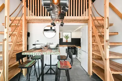 a kitchen with a dining table and stools at Apartma N'Poznam župa in Ljubljana
